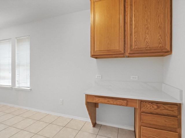 unfurnished office featuring built in desk and light tile patterned flooring