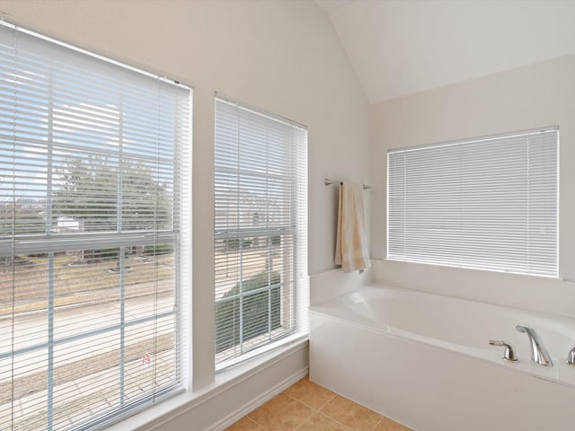 bathroom featuring lofted ceiling, tile patterned flooring, and a tub