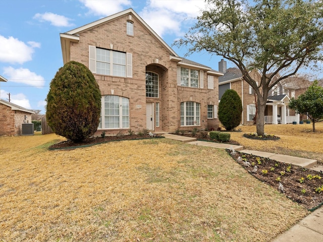 traditional-style house featuring a front lawn, cooling unit, and brick siding