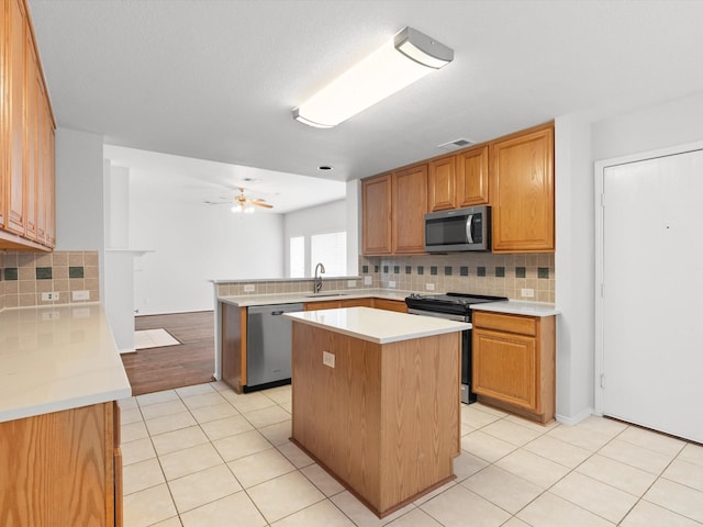 2425 Brycewood Ln, Plano, TX 75025 - kitchen featuring stainless steel appliances, a sink, a peninsula, tasteful backsplash, and light countertops