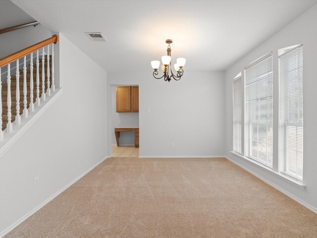 carpeted empty room featuring a chandelier