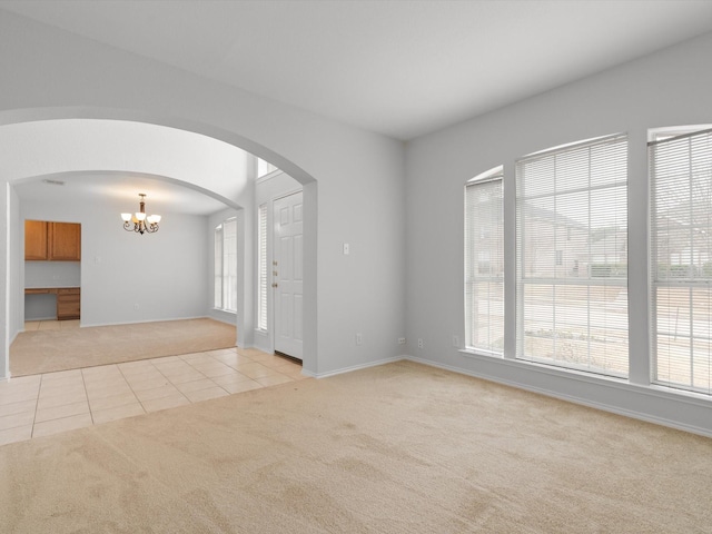 carpeted spare room with a notable chandelier