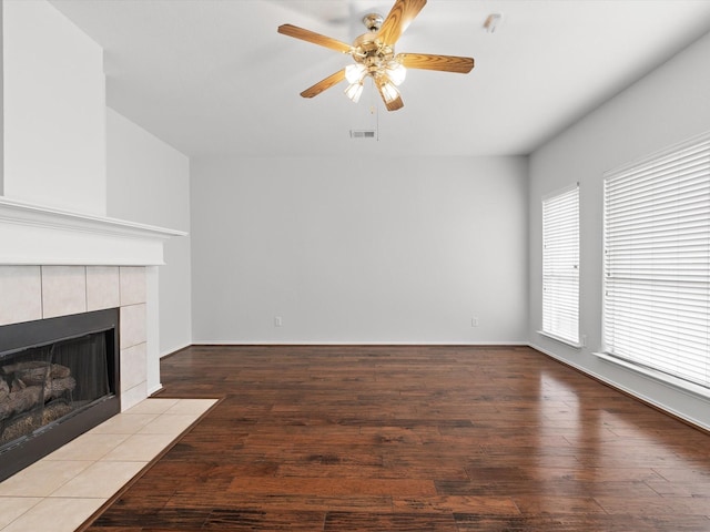 unfurnished living room featuring a tiled fireplace, light hardwood / wood-style flooring, and ceiling fan