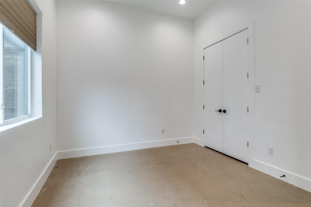 spare room with finished concrete flooring, recessed lighting, and baseboards