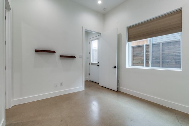 empty room featuring concrete flooring, recessed lighting, and baseboards