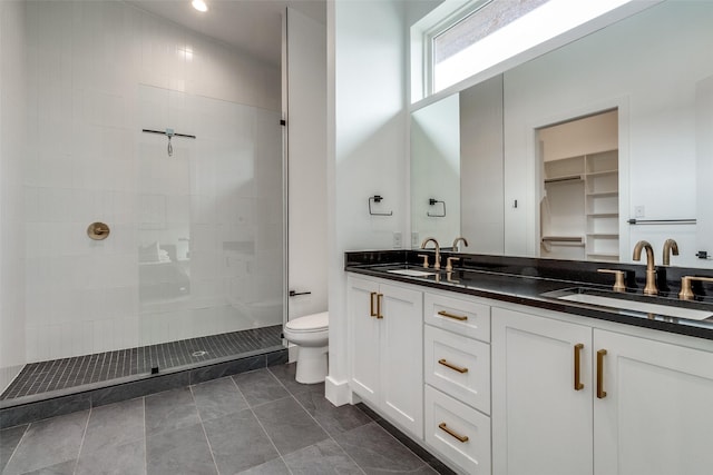 bathroom with double vanity, toilet, walk in shower, and a sink