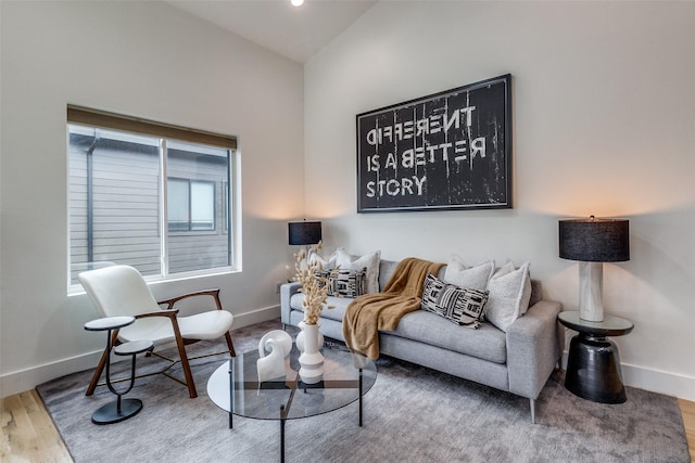 living area featuring vaulted ceiling, wood finished floors, and baseboards