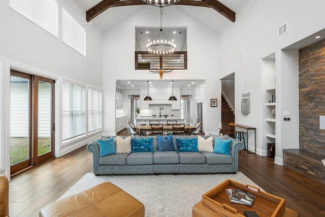 living room with a chandelier, a wealth of natural light, built in shelves, and wood finished floors