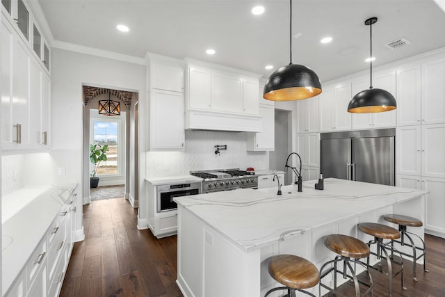 kitchen featuring pendant lighting, high quality appliances, a center island with sink, and white cabinets