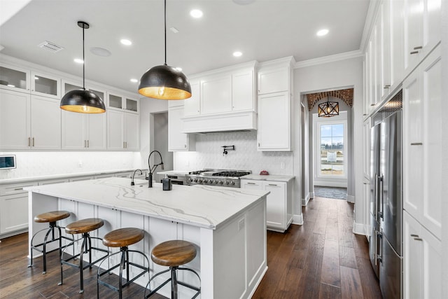 kitchen featuring tasteful backsplash, a center island with sink, crown molding, and white cabinets