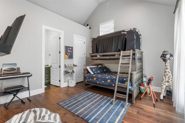 bedroom with ensuite bath, baseboards, wood finished floors, and lofted ceiling