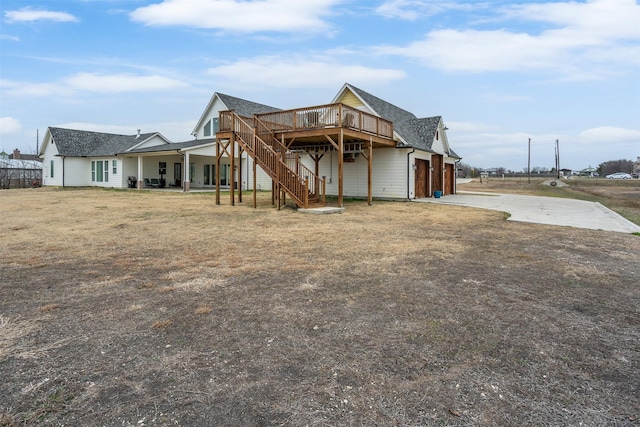 back of property with a garage, a deck, and a lawn