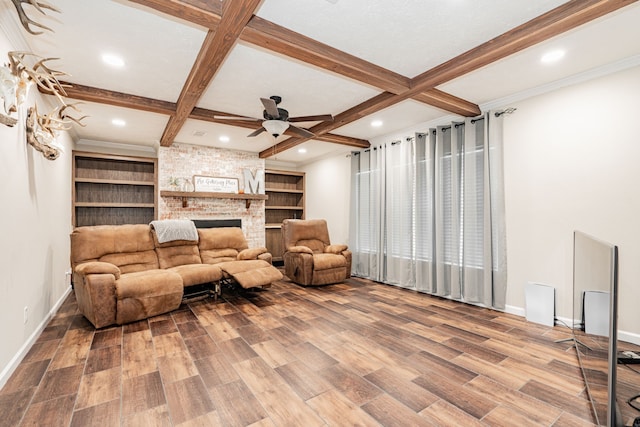 living room featuring hardwood / wood-style floors, a fireplace, beamed ceiling, coffered ceiling, and ceiling fan