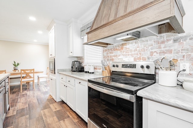 kitchen featuring white cabinetry, tasteful backsplash, light hardwood / wood-style flooring, appliances with stainless steel finishes, and custom range hood