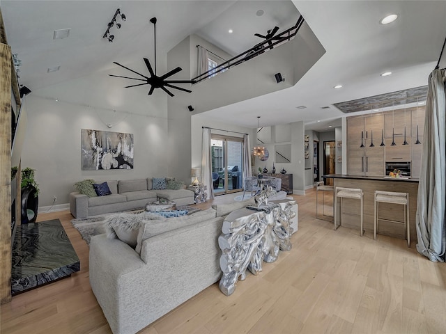 living room with recessed lighting, light wood-style flooring, ceiling fan with notable chandelier, and high vaulted ceiling