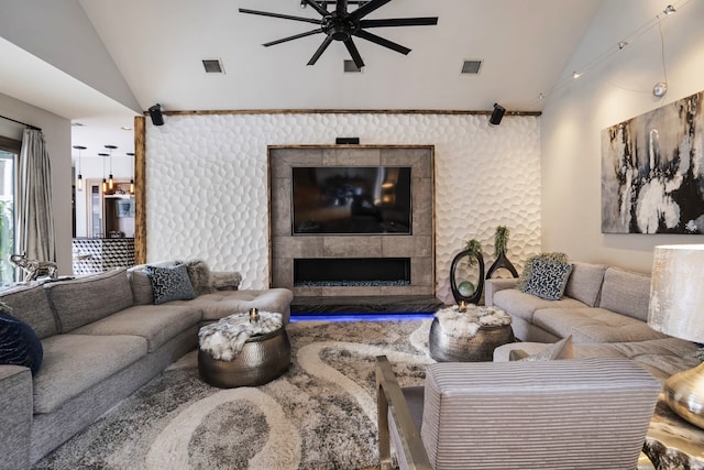 living room with visible vents, lofted ceiling, ceiling fan, and a tiled fireplace