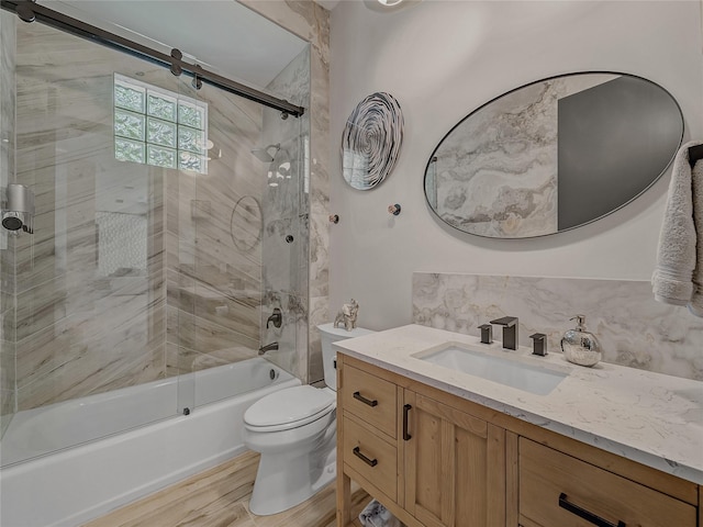 full bath featuring toilet, backsplash, wood finished floors, shower / bath combination with glass door, and vanity