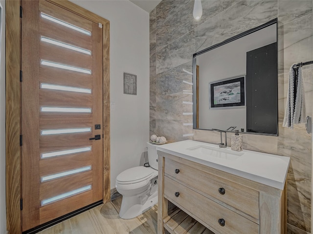 bathroom with vanity, tile walls, and toilet