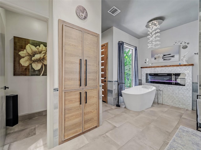 bathroom with a soaking tub, visible vents, and a glass covered fireplace