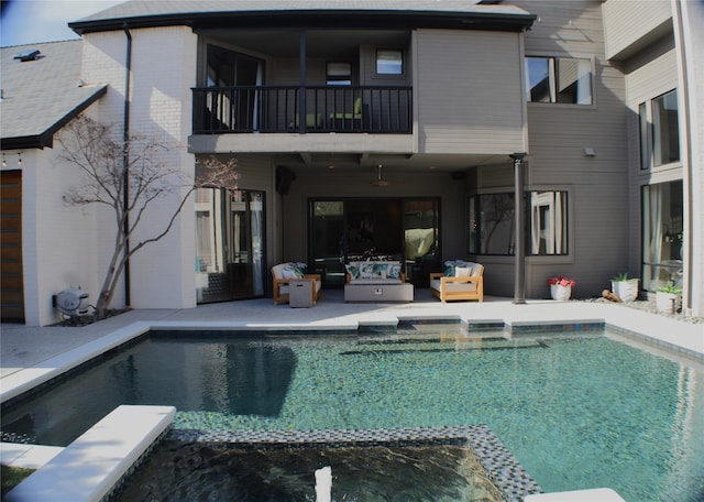 back of property featuring brick siding, an outdoor living space, a pool with connected hot tub, a balcony, and a patio area