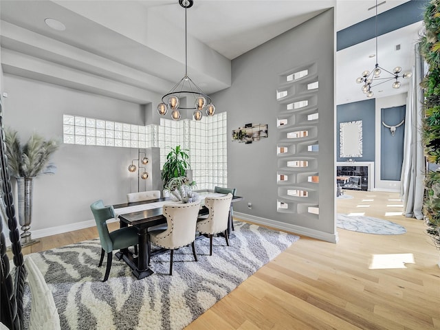 dining space with baseboards, an inviting chandelier, and wood finished floors