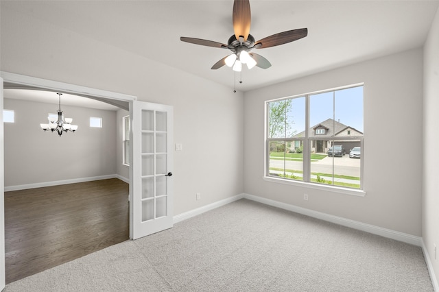 carpeted spare room with baseboards, ceiling fan with notable chandelier, and french doors