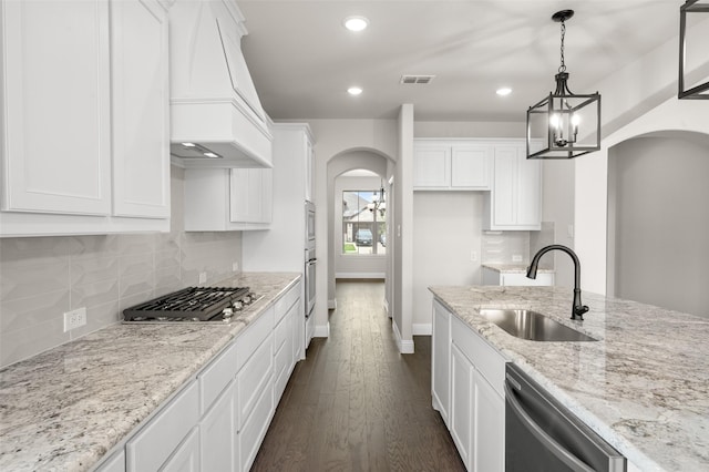 kitchen featuring custom range hood, a sink, visible vents, stainless steel appliances, and arched walkways