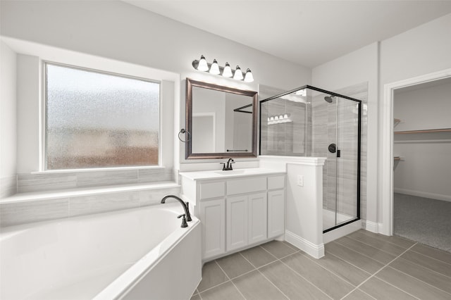 bathroom featuring a shower stall, a bath, vanity, tile patterned flooring, and a walk in closet