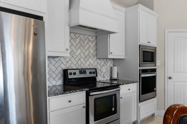 kitchen with premium range hood, white cabinetry, dark stone countertops, appliances with stainless steel finishes, and decorative backsplash