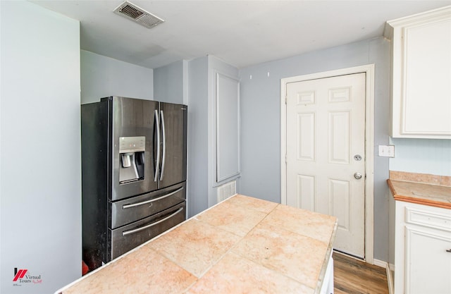 kitchen featuring stainless steel refrigerator with ice dispenser, white cabinetry, and hardwood / wood-style floors