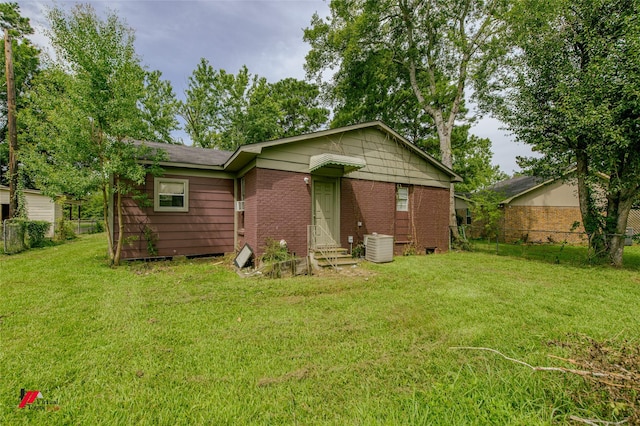 rear view of property featuring a yard and central air condition unit