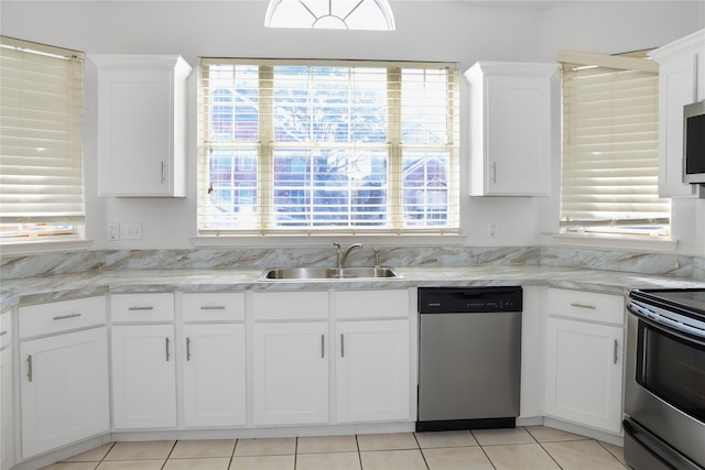 kitchen featuring appliances with stainless steel finishes, sink, white cabinets, light tile patterned floors, and light stone countertops