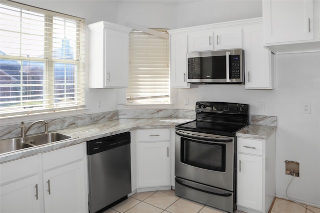 kitchen with appliances with stainless steel finishes, sink, white cabinets, and plenty of natural light