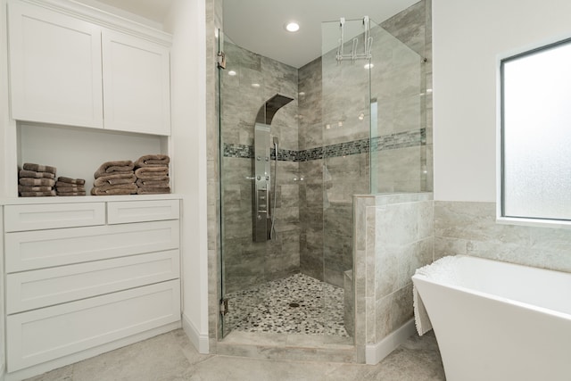 bathroom with a healthy amount of sunlight, separate shower and tub, and tile walls