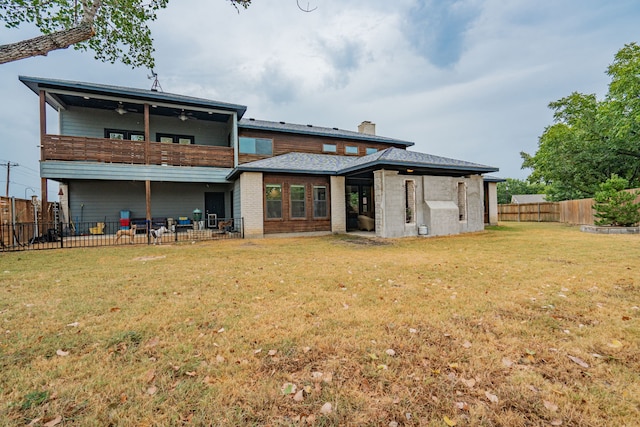 rear view of property with a balcony, ceiling fan, and a lawn