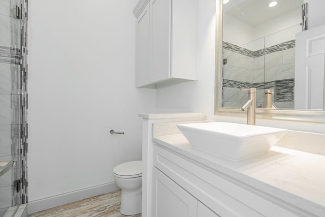 bathroom with a shower with door, vanity, hardwood / wood-style flooring, and toilet