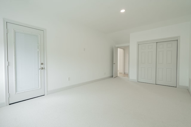 unfurnished bedroom featuring light colored carpet and a closet