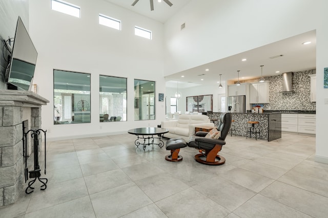 tiled living room with ceiling fan and a stone fireplace