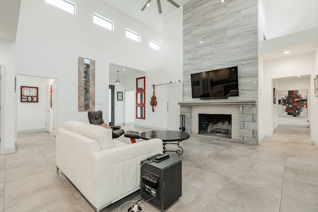 living room featuring a high ceiling, a large fireplace, light tile patterned floors, and ceiling fan