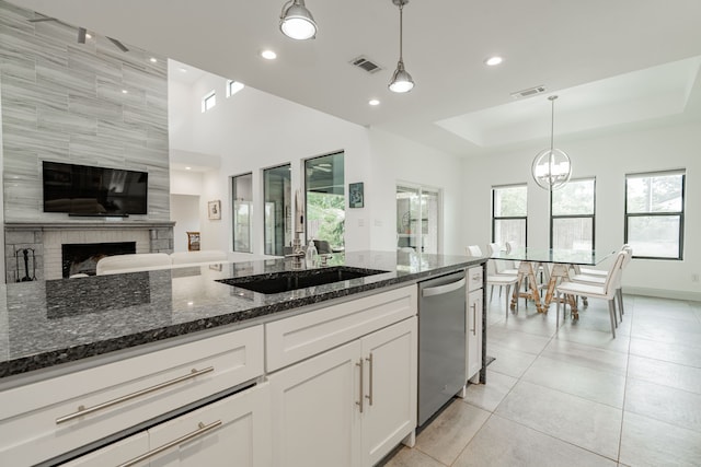 kitchen featuring hanging light fixtures, white cabinetry, stainless steel dishwasher, and dark stone countertops