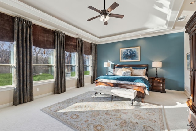 bedroom with ornamental molding, light colored carpet, ceiling fan, and a tray ceiling