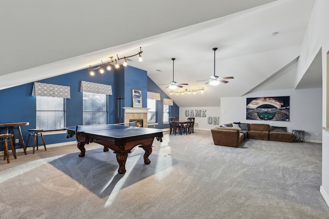 game room with high vaulted ceiling, track lighting, carpet flooring, a tile fireplace, and ceiling fan