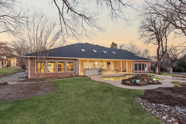 back house at dusk with a yard and a patio area