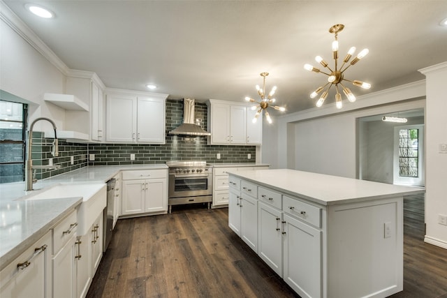 kitchen with wall chimney exhaust hood, a kitchen island, pendant lighting, stainless steel appliances, and white cabinets