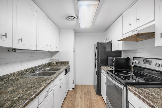 kitchen featuring sink, light wood-type flooring, appliances with stainless steel finishes, dark stone counters, and white cabinets