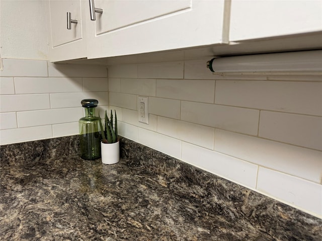 interior details with backsplash, dark stone counters, and white cabinets