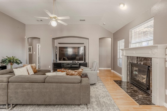 living room with hardwood / wood-style flooring, lofted ceiling, a high end fireplace, and ceiling fan