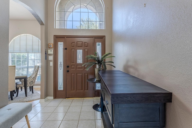 foyer entrance with light tile patterned flooring and a towering ceiling