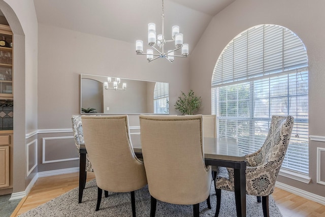 dining room featuring lofted ceiling, a notable chandelier, and light hardwood / wood-style flooring