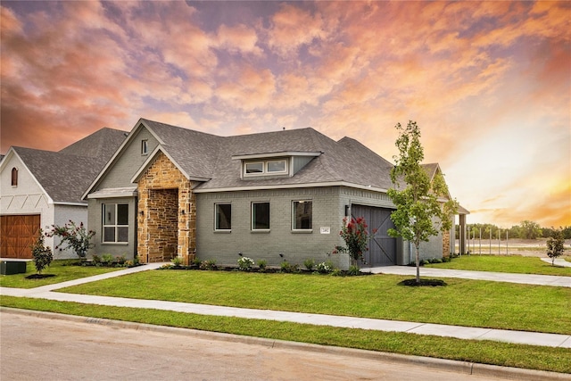 view of front of property featuring a garage, a yard, and central AC unit